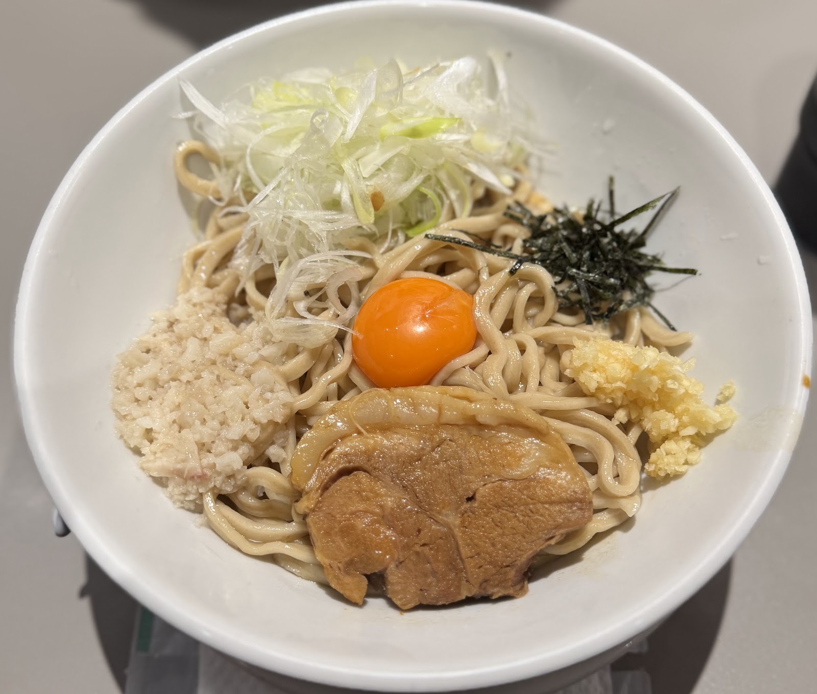 汁なしの太麺に卵黄、チャーシュー、背脂、ニンニク、刻み海苔、白髪ねぎ。