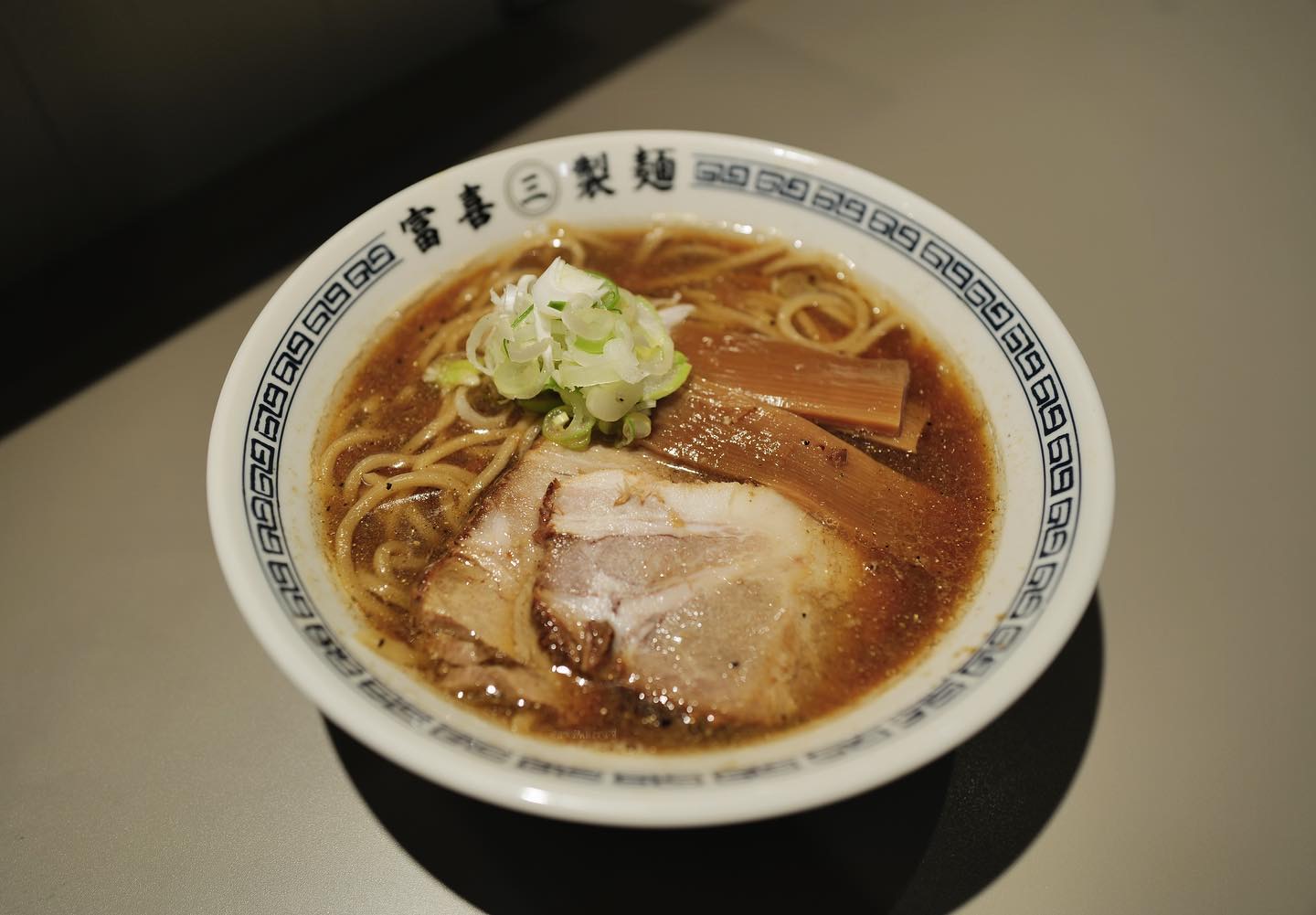 富喜製麺研究所 六本木店の中華そば。チャーシュー、メンマ、ねぎがのった醤油色のスープ。青い雷紋の縁の「富喜㊂製麺」の丼。